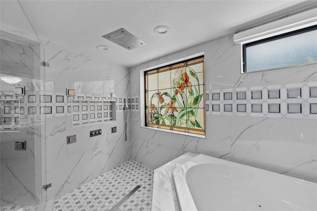 bathroom with plus walk in shower, a textured ceiling, and tile walls