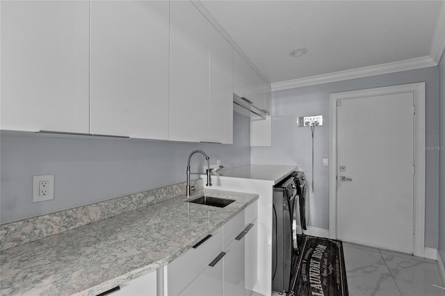 laundry room featuring cabinets, ornamental molding, sink, and washing machine and clothes dryer