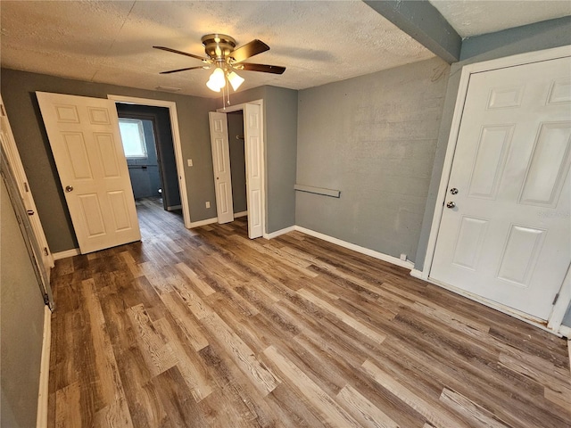 unfurnished bedroom featuring a textured ceiling, wood-type flooring, and ceiling fan