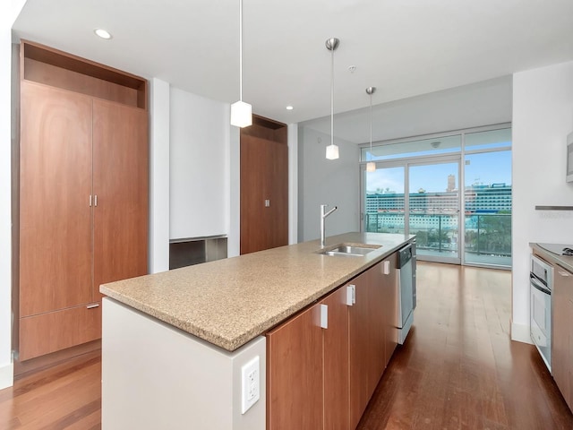 kitchen featuring wood-type flooring, pendant lighting, a center island with sink, and sink