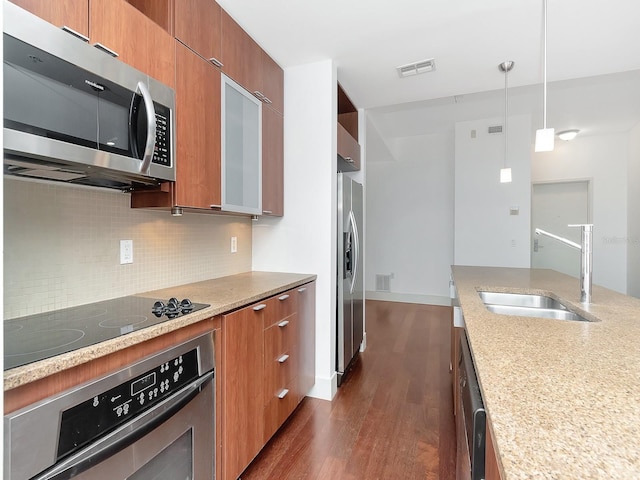 kitchen with appliances with stainless steel finishes, backsplash, dark wood-type flooring, sink, and pendant lighting