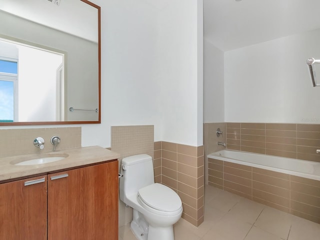 bathroom with tile patterned floors, vanity, toilet, and tiled bath