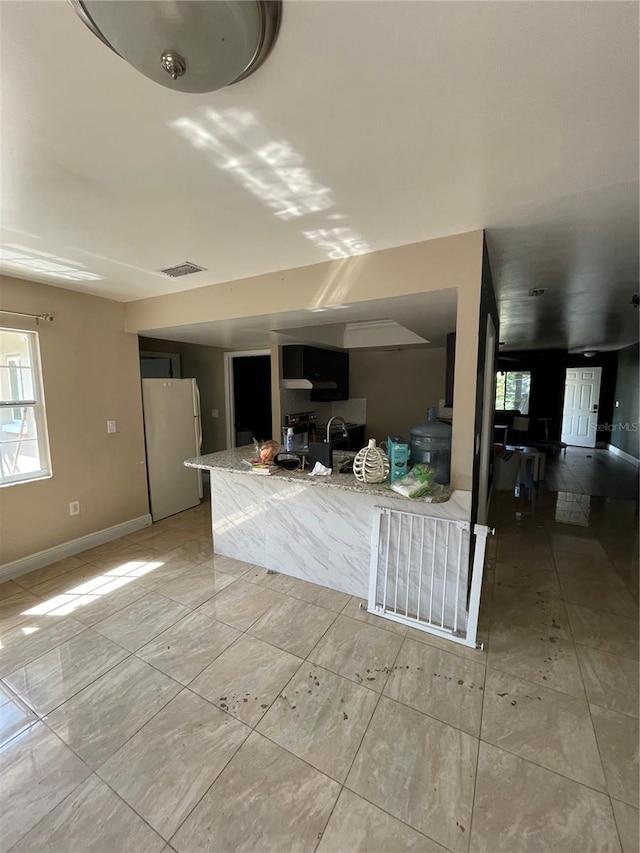 kitchen featuring white fridge, sink, and light stone countertops