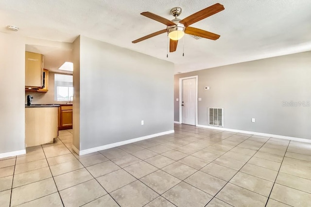 tiled empty room with ceiling fan and a textured ceiling