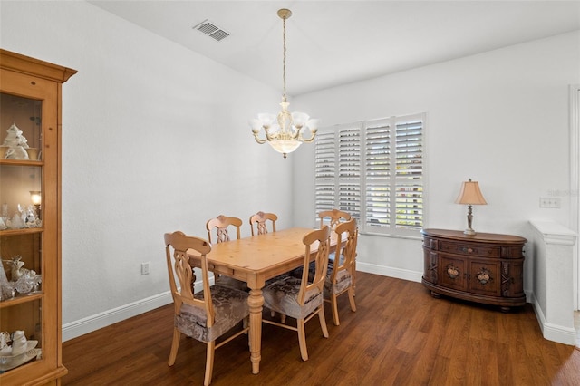 dining space featuring dark wood-type flooring and an inviting chandelier