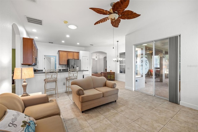 living room featuring ceiling fan with notable chandelier and light tile patterned floors