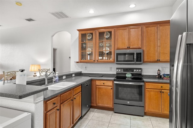 kitchen with light tile patterned floors, stainless steel appliances, sink, and kitchen peninsula