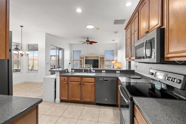 kitchen with light tile patterned floors, stainless steel appliances, sink, ceiling fan with notable chandelier, and decorative light fixtures