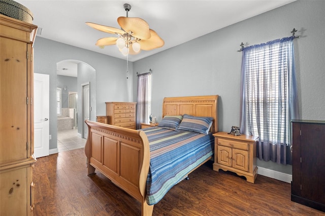 bedroom with ceiling fan, multiple windows, dark hardwood / wood-style floors, and ensuite bath