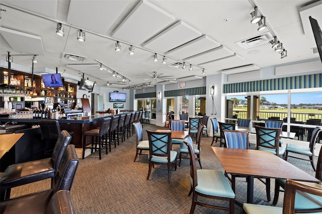 carpeted dining space with ceiling fan and indoor bar