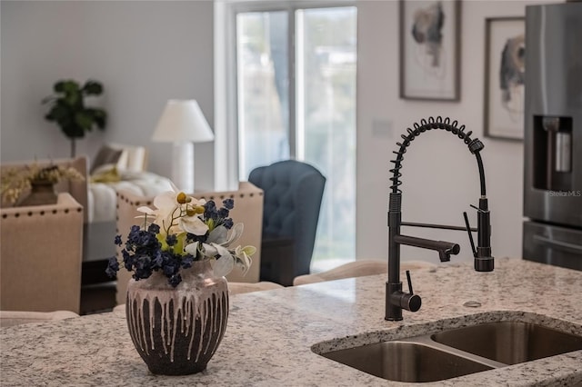 interior space featuring stainless steel fridge, light stone countertops, and sink