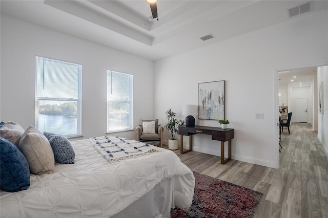 bedroom featuring a tray ceiling, ceiling fan, and light hardwood / wood-style flooring