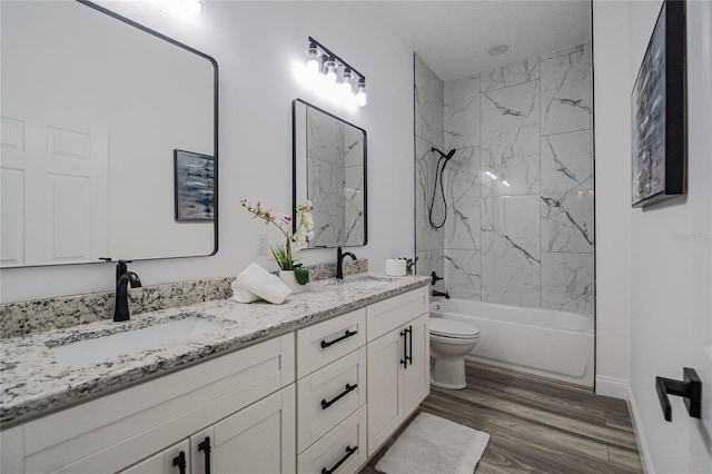 full bathroom featuring hardwood / wood-style floors, tiled shower / bath combo, toilet, and vanity