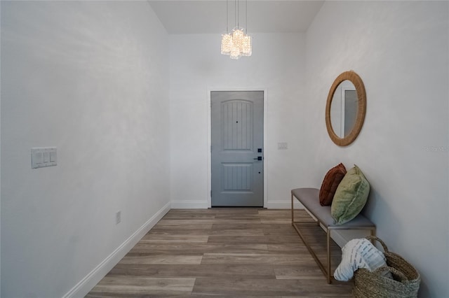 foyer entrance with a chandelier, light wood-style flooring, and baseboards