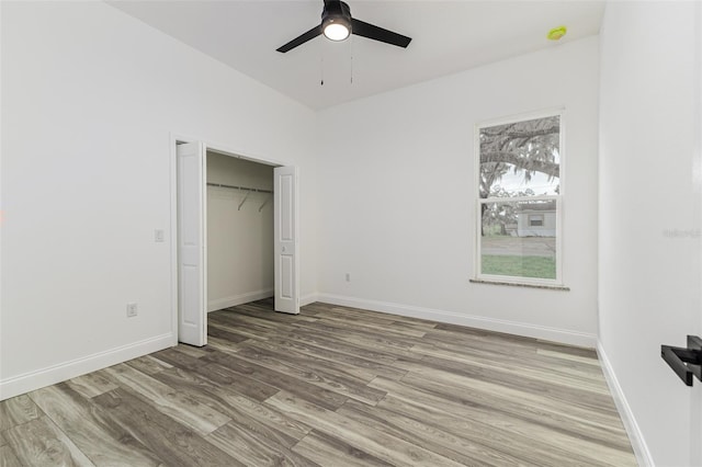 unfurnished bedroom featuring a ceiling fan, a closet, light wood-style flooring, and baseboards