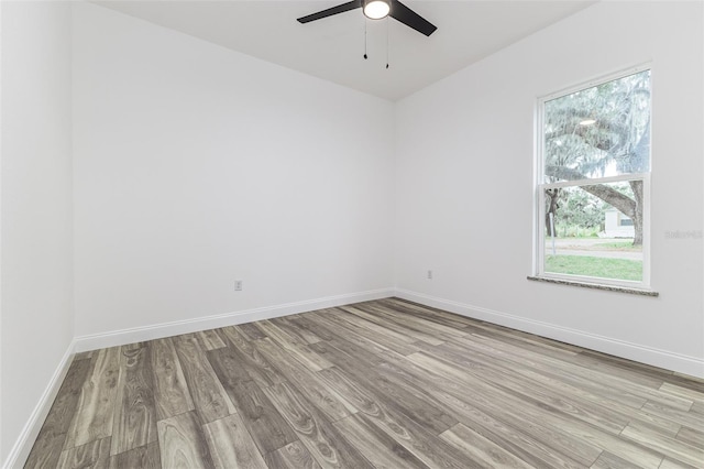 empty room featuring a ceiling fan, light wood-type flooring, and baseboards