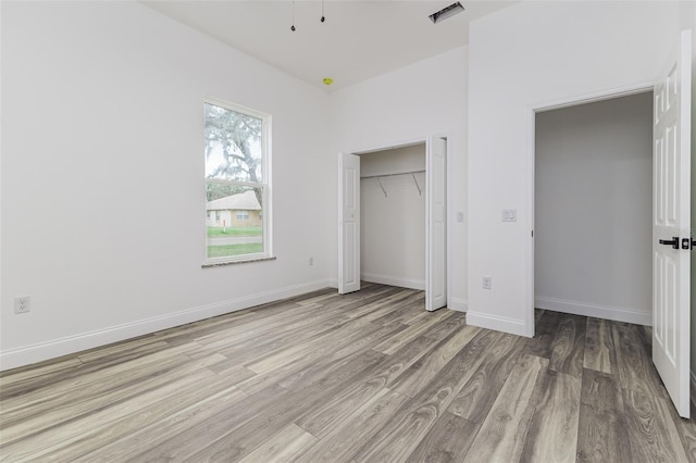 unfurnished bedroom featuring a closet, visible vents, light wood-style flooring, and baseboards