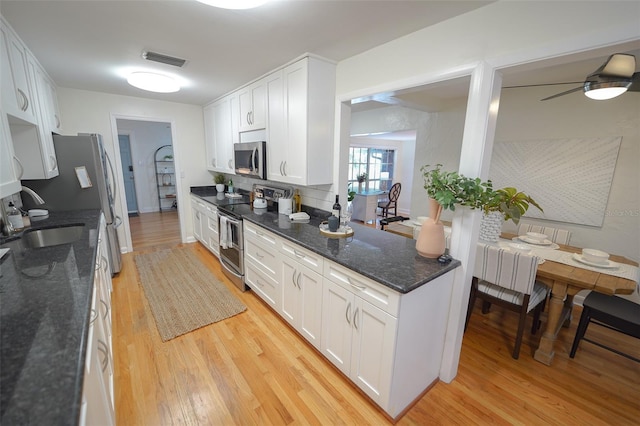 kitchen with white cabinets, light wood-type flooring, sink, and appliances with stainless steel finishes