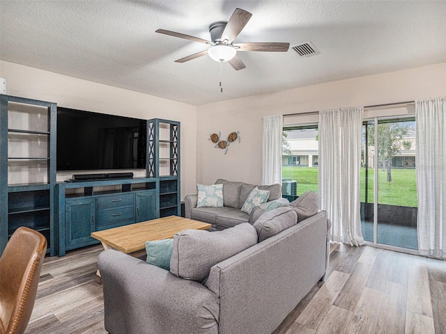 living room featuring ceiling fan, a textured ceiling, and light hardwood / wood-style flooring