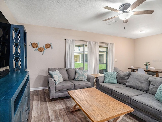 living room with hardwood / wood-style floors, a textured ceiling, and ceiling fan