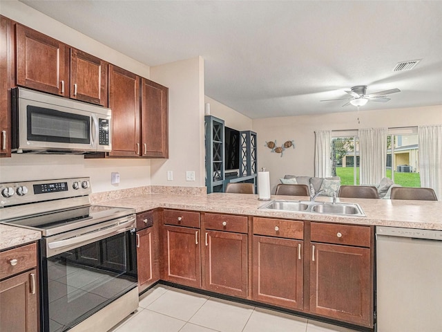 kitchen featuring sink, kitchen peninsula, ceiling fan, stainless steel appliances, and light tile patterned floors