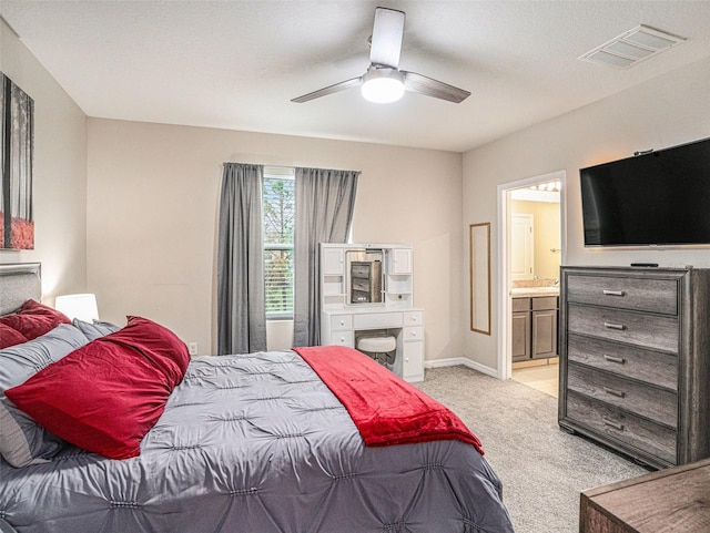 bedroom with ensuite bath, light carpet, and ceiling fan