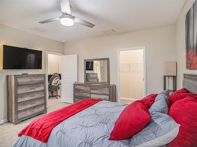 carpeted bedroom with a walk in closet, a closet, and ceiling fan