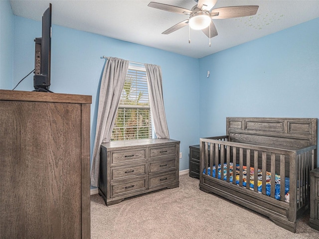 carpeted bedroom with a textured ceiling, a crib, and ceiling fan