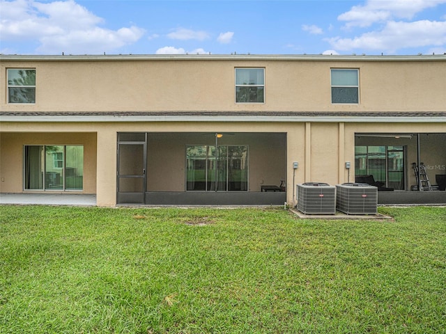 back of house with central AC unit and a lawn