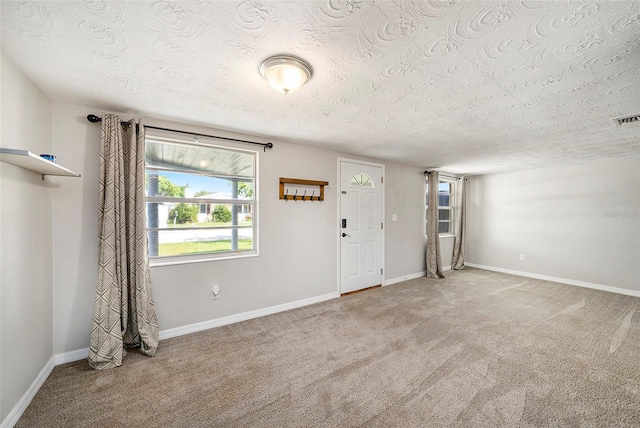 carpeted foyer featuring a textured ceiling