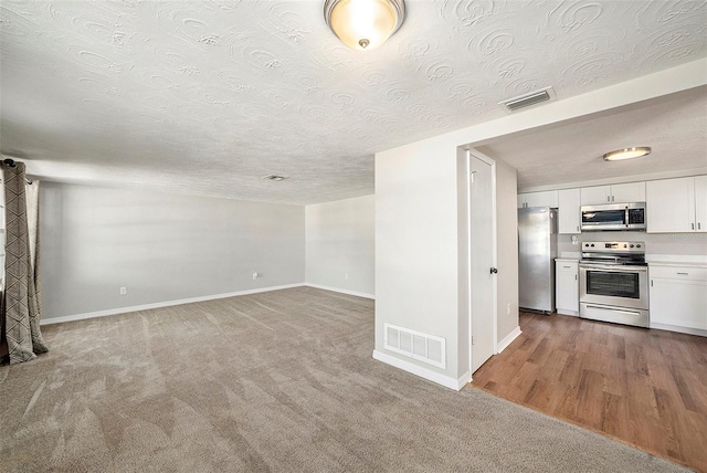 unfurnished living room with wood-type flooring and a textured ceiling