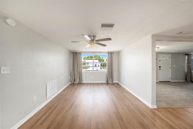 empty room featuring ceiling fan, a textured ceiling, and light wood-type flooring