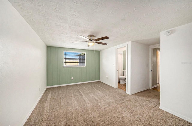 unfurnished bedroom with ensuite bath, carpet, a textured ceiling, and ceiling fan