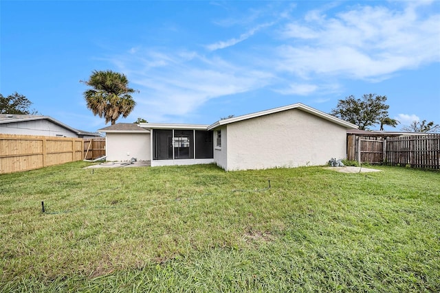 back of property with a yard and a sunroom