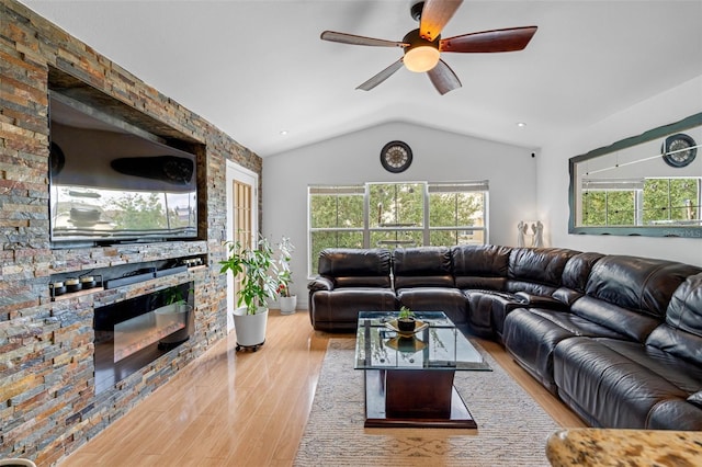 living room featuring ceiling fan, lofted ceiling, light wood-type flooring, and a fireplace