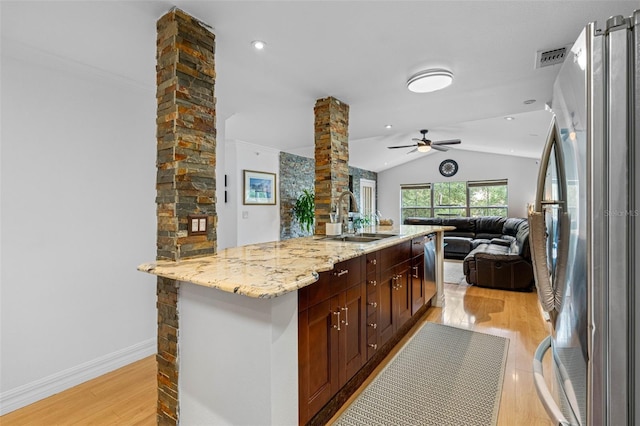 kitchen featuring decorative columns, stainless steel appliances, light wood-style flooring, open floor plan, and a sink