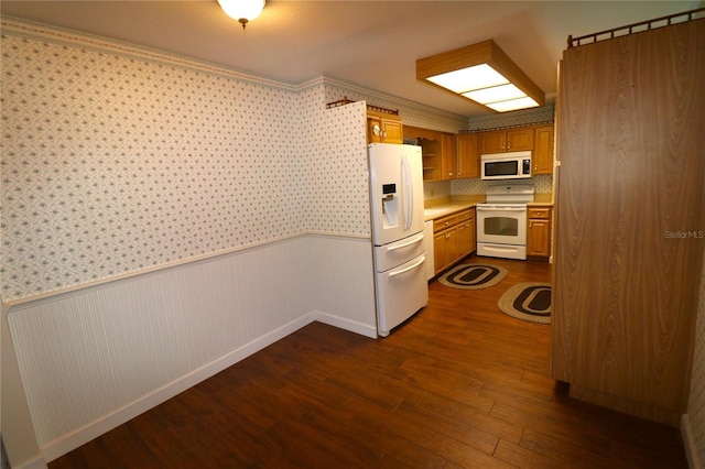 kitchen with dark wood finished floors, wallpapered walls, a wainscoted wall, light countertops, and white appliances