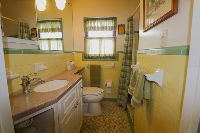 bathroom with toilet, vanity, tile walls, and tile patterned flooring