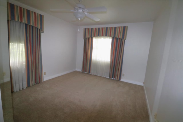 carpeted empty room with a ceiling fan and baseboards