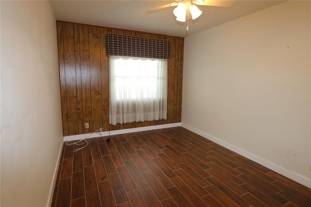 empty room with baseboards, a ceiling fan, and dark wood-style floors
