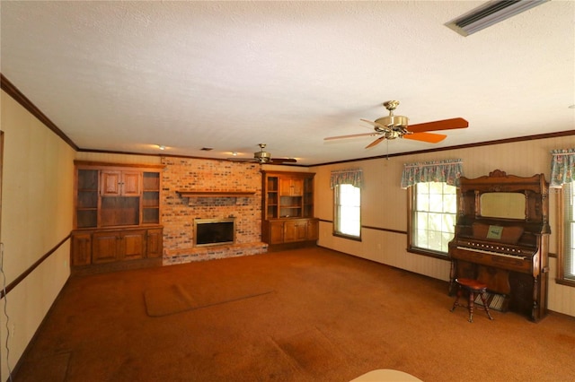 unfurnished living room featuring ceiling fan, a textured ceiling, carpet flooring, a brick fireplace, and ornamental molding