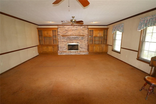 unfurnished living room with crown molding, a brick fireplace, light colored carpet, and ceiling fan