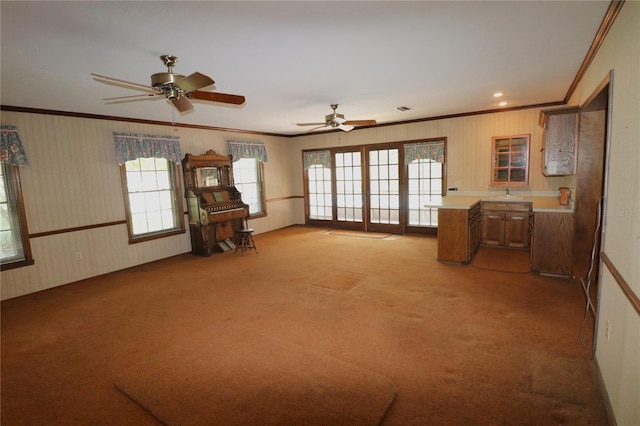 living room with a ceiling fan, light carpet, ornamental molding, and wallpapered walls