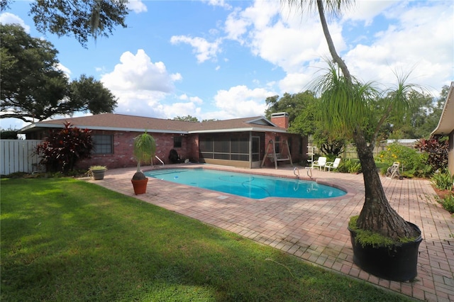 view of pool with a yard, a patio area, a sunroom, and a fenced in pool