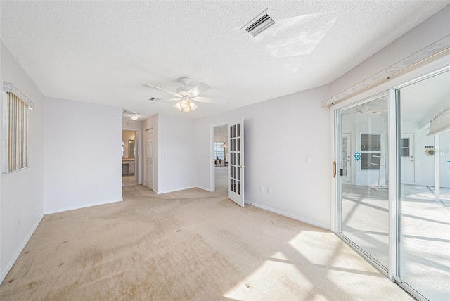 carpeted spare room with french doors, a textured ceiling, and ceiling fan