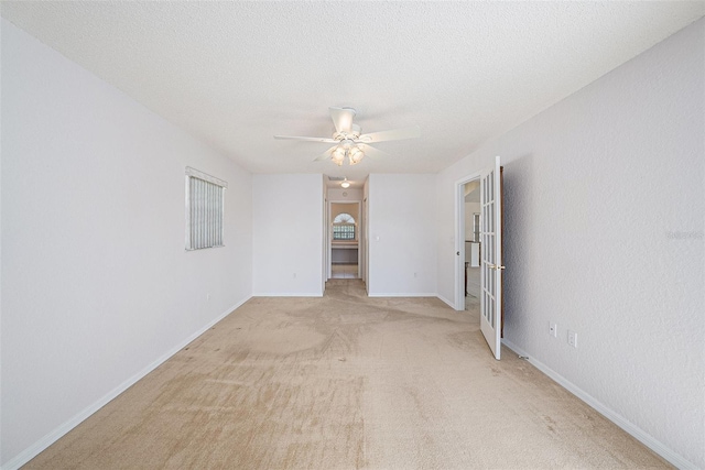 carpeted spare room featuring a textured ceiling and ceiling fan