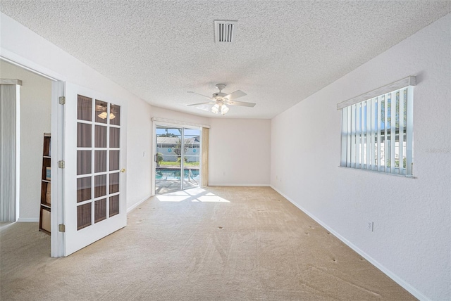 spare room with light carpet, ceiling fan, and a textured ceiling