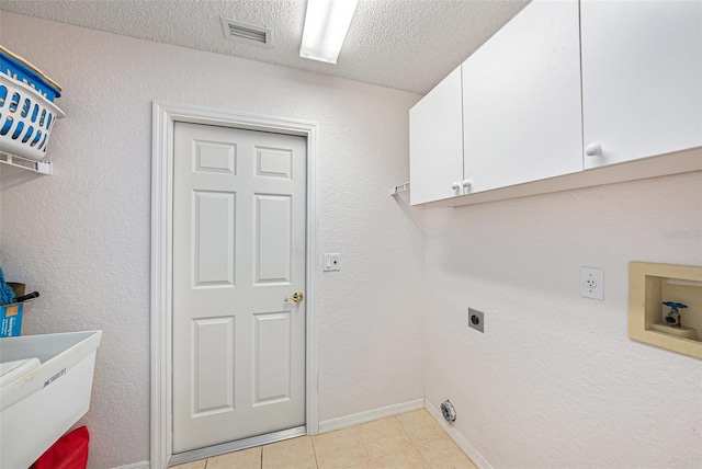 clothes washing area featuring hookup for a washing machine, electric dryer hookup, cabinets, light tile patterned floors, and a textured ceiling