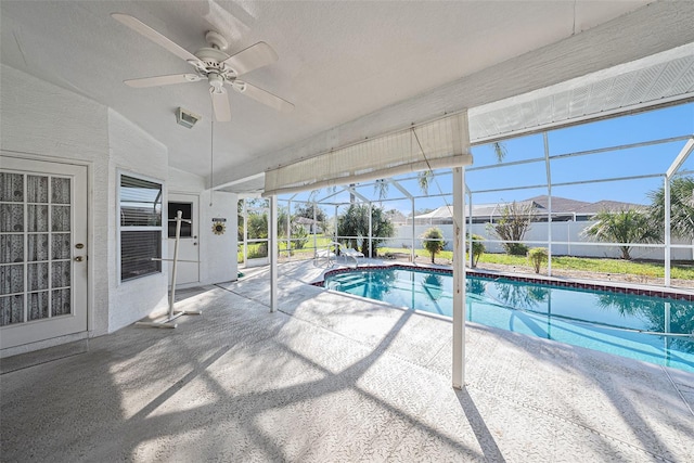 view of swimming pool with glass enclosure, ceiling fan, and a patio area