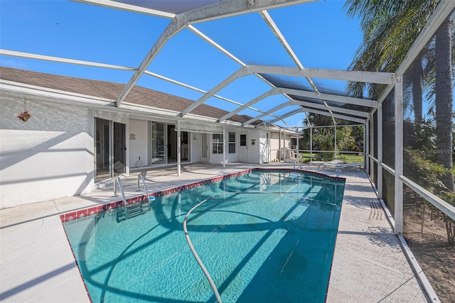 view of swimming pool featuring glass enclosure and a patio